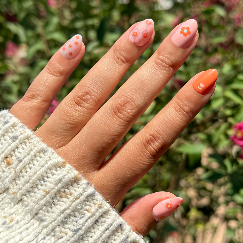 Hand with Mixed Quilt Print - Press-On | Short | Almond nails featuring peach floral and diamond quilt designs for an easy mani