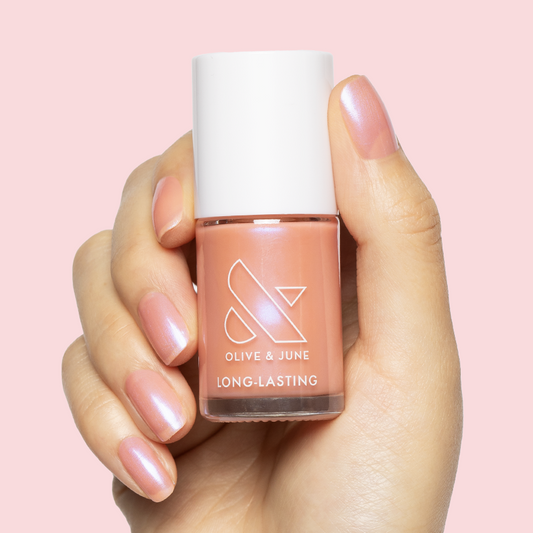 Hand holding Olive and June Olive Y'all nail polish with sheer pink-blue iridescent gel polish manicure