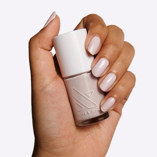 Hand holding a bottle of TT gel polish in almost pastel lavender with grey undertones for a delicate manicure
