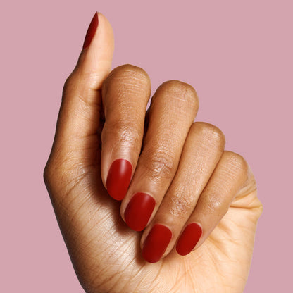 Hand with nails coated in deep red matte finish using The Matte Top Coat for a smooth, durable manicure look
