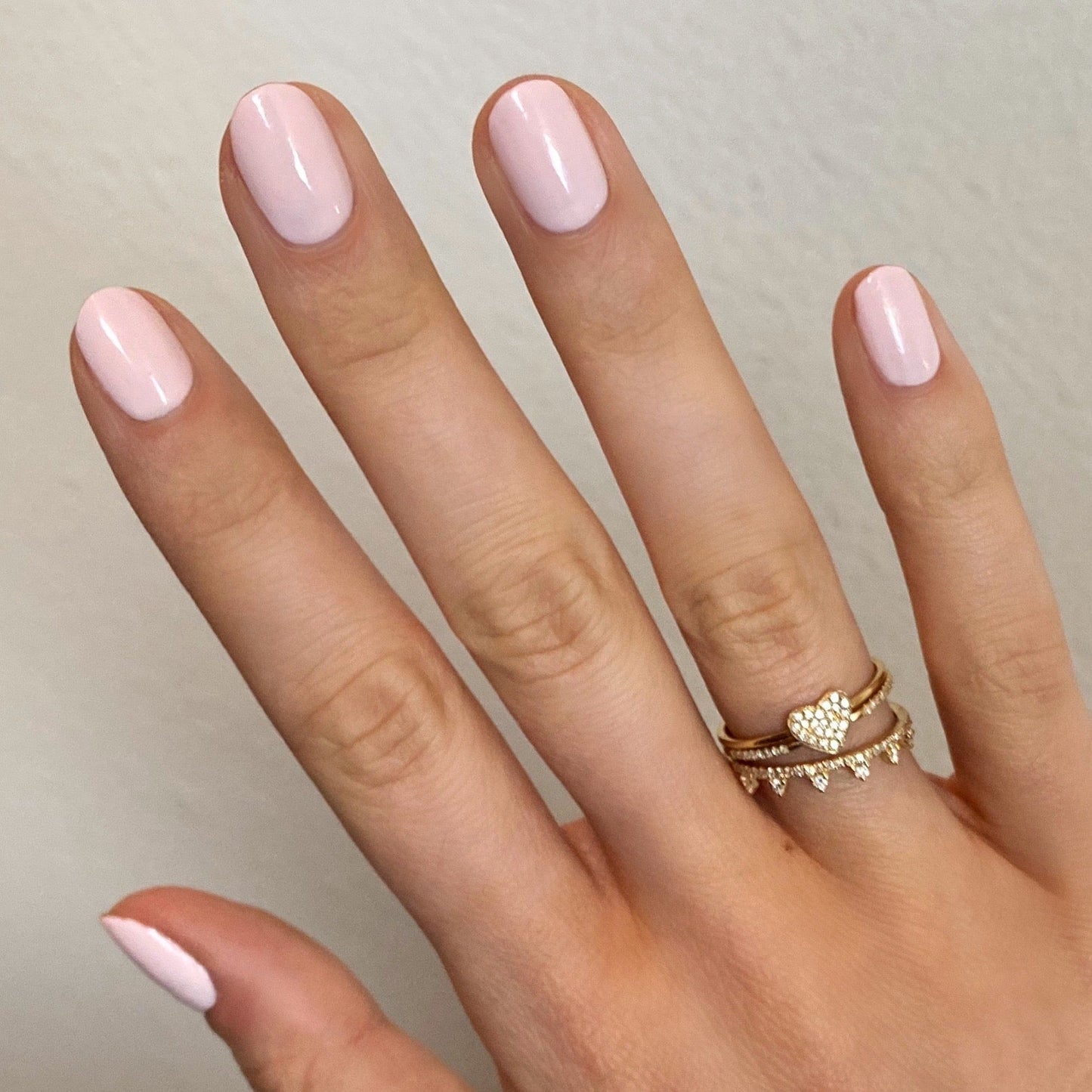 Hand with nails painted in GH, a soft opaque baby pink polish ideal for a radiant and versatile manicure at home