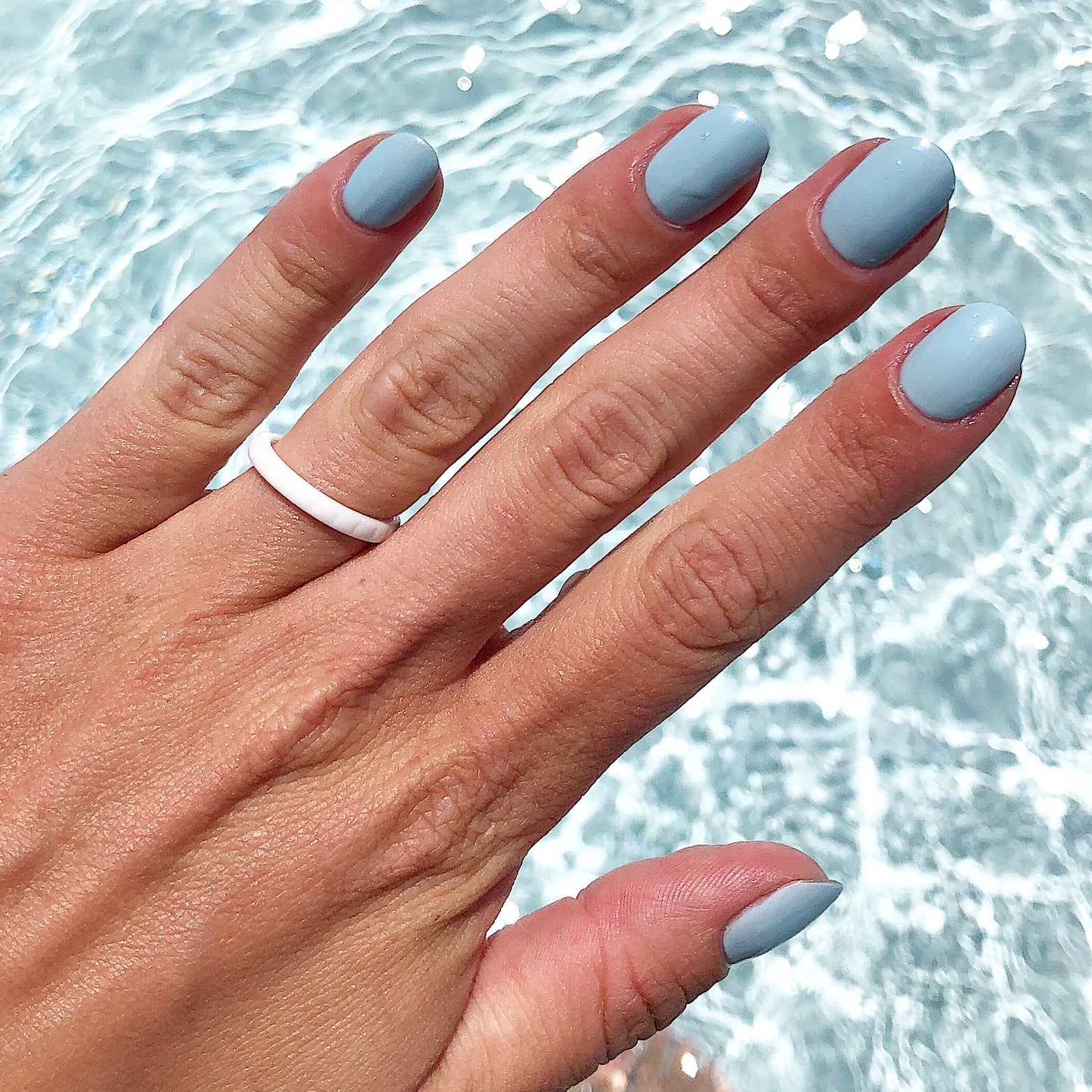 Hand with nails painted in Honest & True gel polish in serene blue for a soothing at-home manicure look