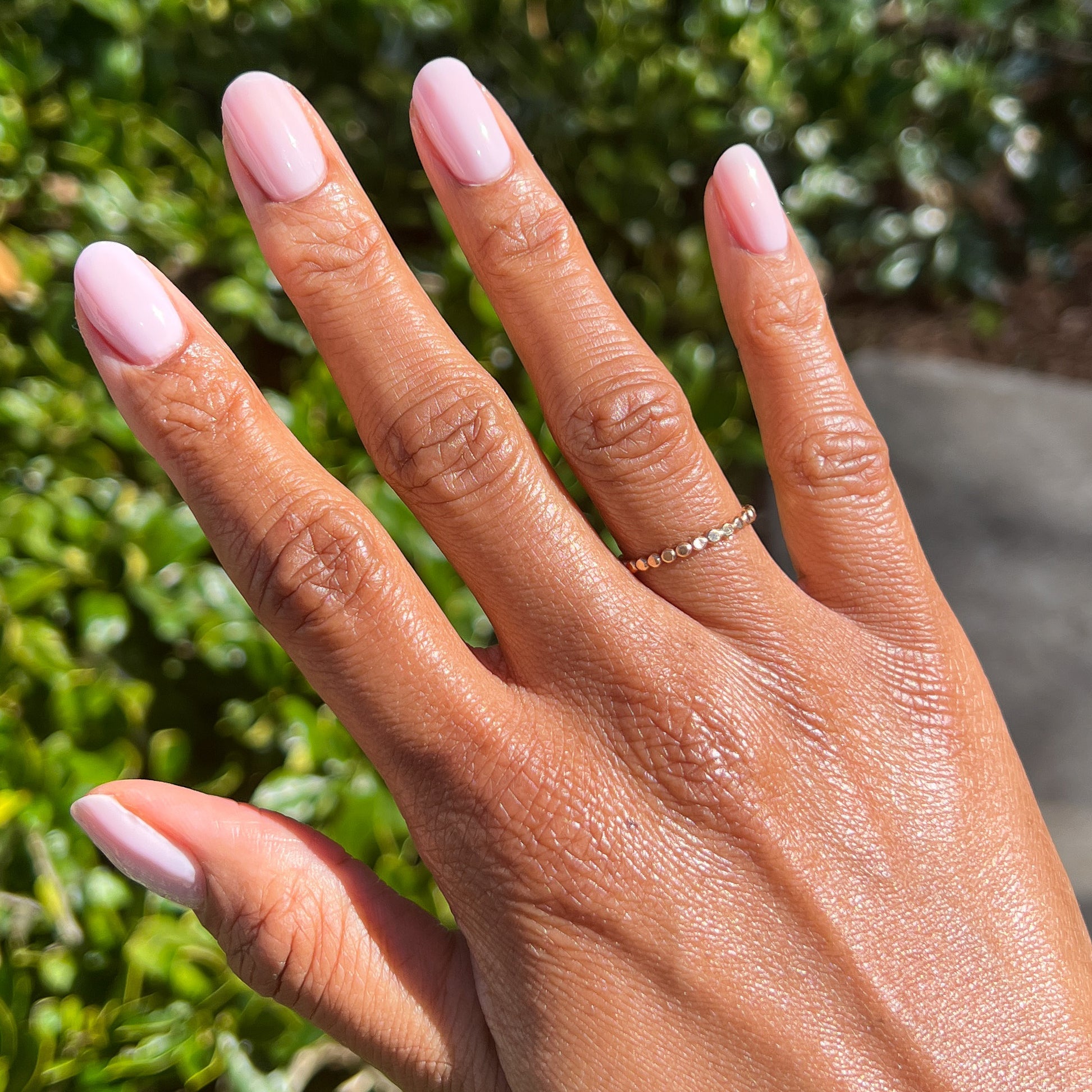 Hand with nails painted in cool sheer pink Strawberry Scone polish for a natural, long-lasting Olive and June manicure