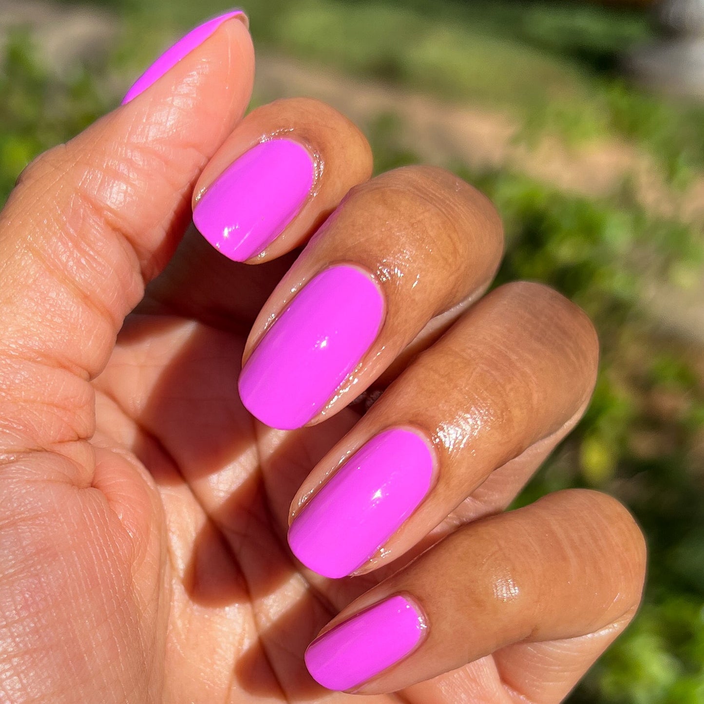 Hand with nails coated in vibrant soft magenta Jam, Please polish for a glossy, long-lasting manicure by Olive and June
