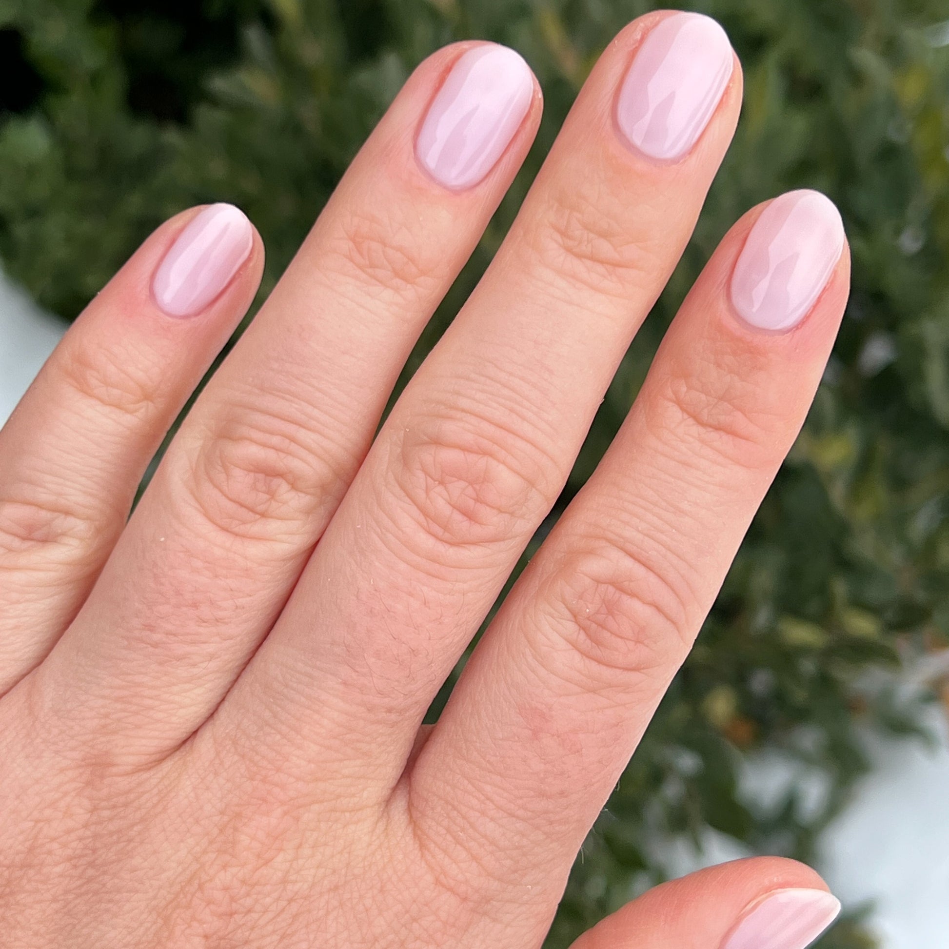 Hand with nails polished in cool sheer pink Strawberry Scone for a natural, long-lasting manicure at home