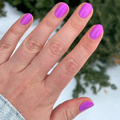 Hand with nails coated in vibrant glowing magenta Jam, Please polish for a smooth long-lasting manicure by Olive and June
