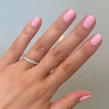 Hand with nails coated in SE polish by Olive and June, showcasing a bright and soft pink manicure perfect for summer at home