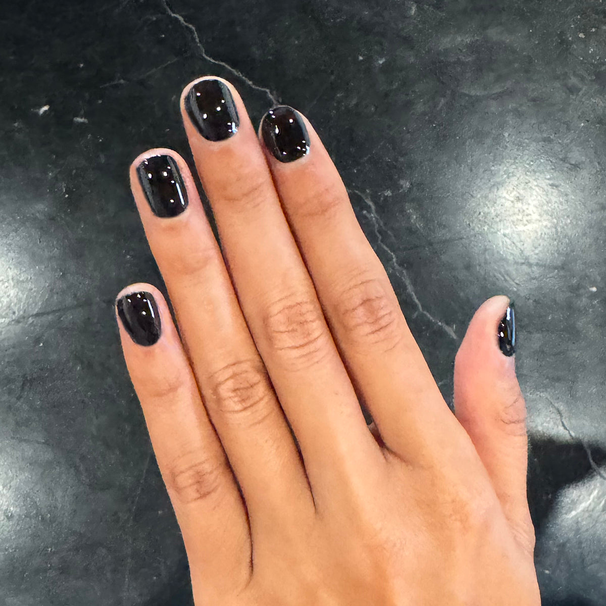 E+M - Gel shown on hand with glossy deep black nails for a sleek and long-lasting manicure by Olive and June