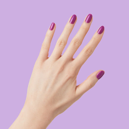 Hand with nails painted vibrant purple Grape Soda polish showing smooth, glossy manicure against lavender background