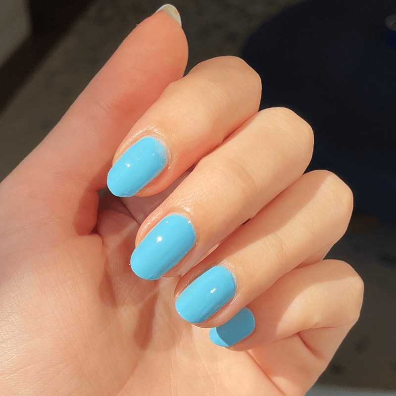 Hand displaying nails coated in smooth, glossy Megababe Blue gel polish for a fresh, confident manicure look