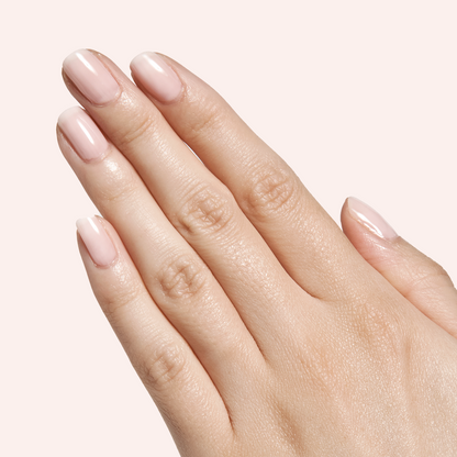 Hand with neutral milky pink Dream Job - Gel polished manicure on soft pale pink background