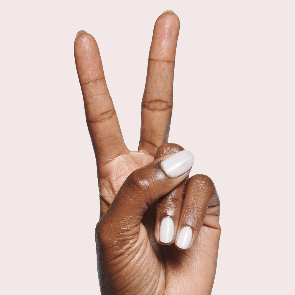 Hand with short nails painted in Sculpture Wing - Gel showing a cool lavender neutral polish on medium brown skin tone