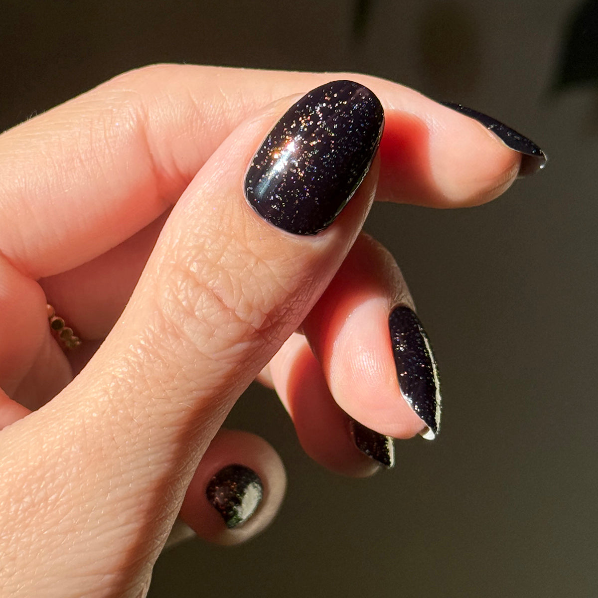 The Pixie Effect Top Coat enhancing black polish with sparkling iridescent shimmer for a radiant manicure look