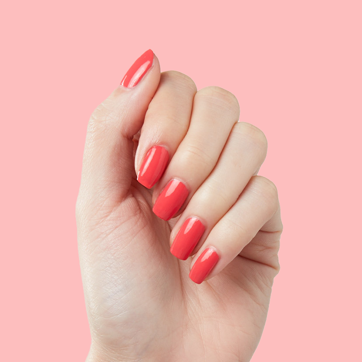 Hand with smooth nails painted in Field Day juicy watermelon red for a bright, long-lasting manicure look