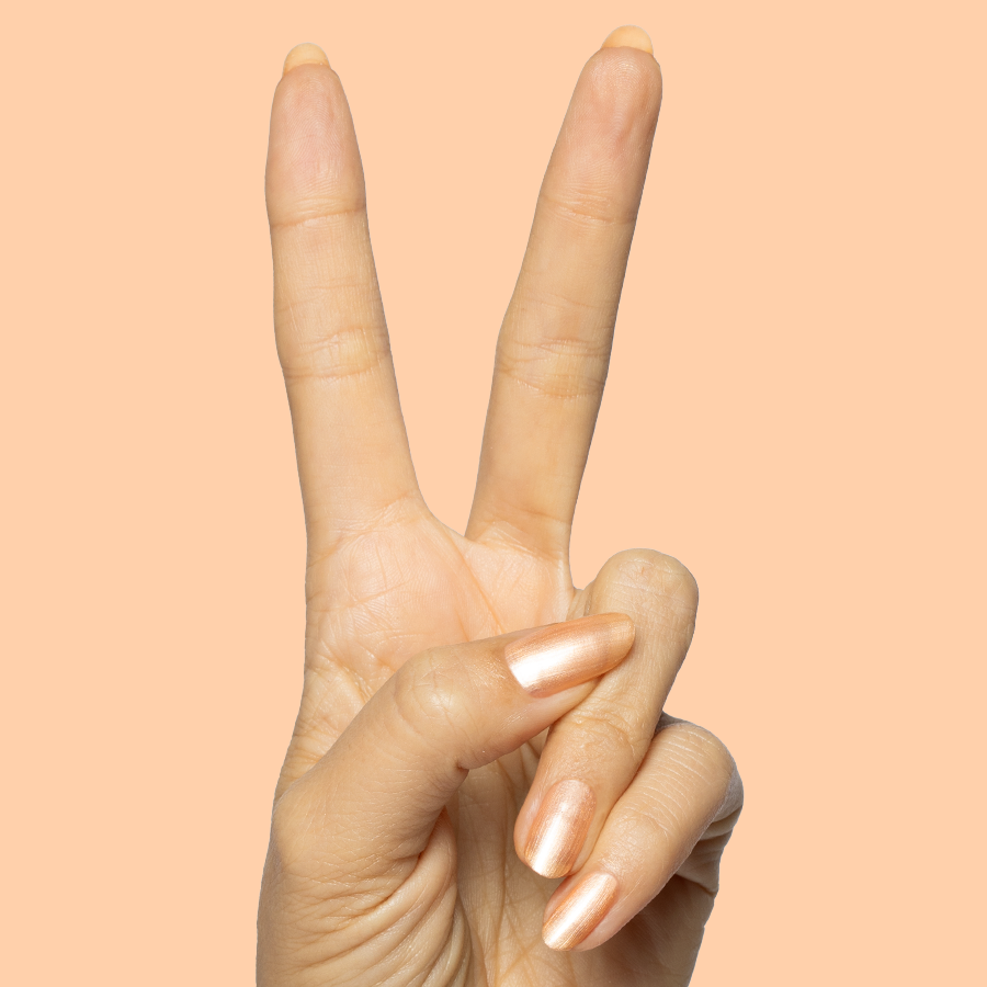 Hand with natural nails painted in Sunlit warm golden peach shimmer gel polish showing peace sign on peach background