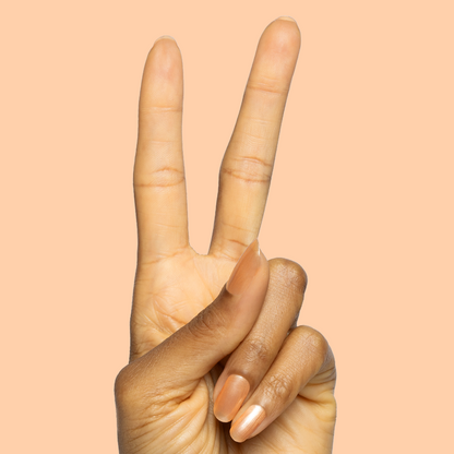 Hand showing peace sign with nails painted in Sunlit warm golden peach shimmer gel polish on soft peach background