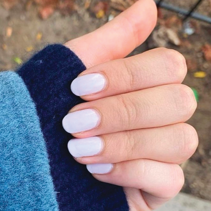 Hand with nails painted in TT, a soft lavender gel polish with balanced grey undertones for a chic at-home manicure