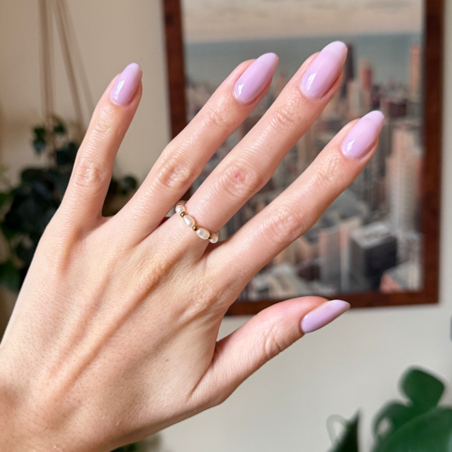 Hand with long almond-shaped nails painted in Dreamy sheer milky pastel lavender gel polish for an elegant manicure look