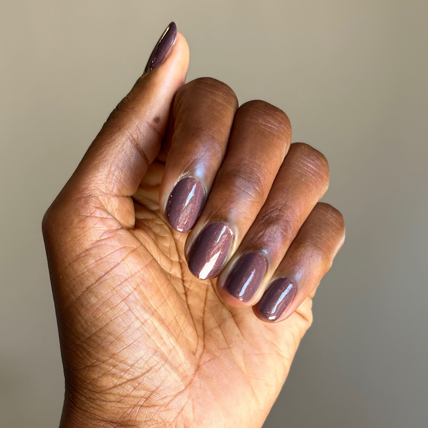 Hand with natural skin tone showing a glossy Goal Getter - Gel manicure with subtle golden shimmer on medium nails